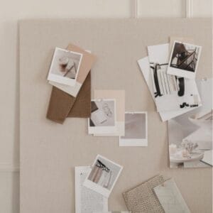 Bulletin board with various neutral-toned photos and fabric swatches pinned, including images of coffee, clothes, and decor.