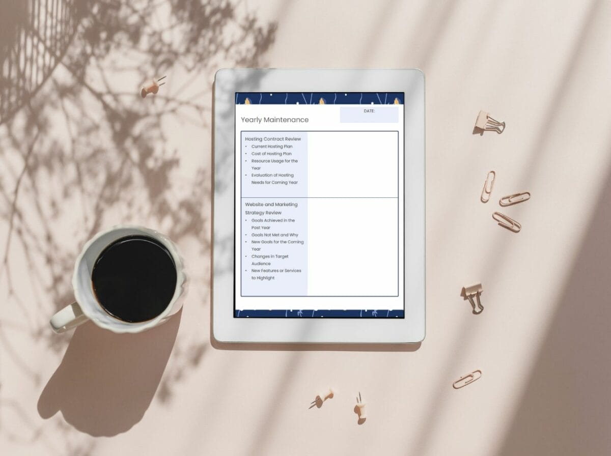 A tablet displaying a yearly maintenance checklist sits on a light pink surface next to a cup of black coffee, with paper clips and binder clips scattered nearby.