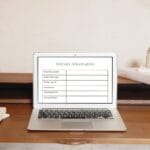 A laptop on a wooden desk displays a website information table with categories such as domain name, hosting details, and installed plugins.